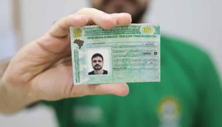Homem exibindo a Carteira Nacional de Habilitação brasileira em destaque para a câmera