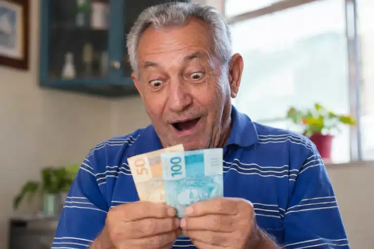 Idoso segurando notas de dinheiro, representando o pagamento de R$ 8.475,55 do INSS e da segunda parcela do 13º nesta semana