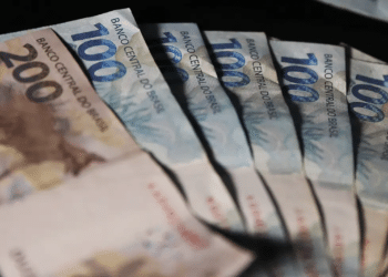 Cédulas de duzentos e cem reais dispostas em formato de leque sobre fundo escuro