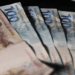 Cédulas de duzentos e cem reais dispostas em formato de leque sobre fundo escuro