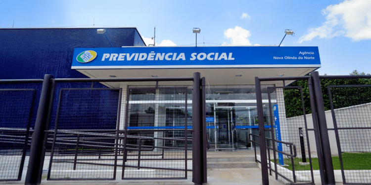 Fachada de uma agência da Previdência Social com grade na entrada e céu azul ao fundo.