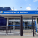 Fachada de uma agência da Previdência Social com grade na entrada e céu azul ao fundo.