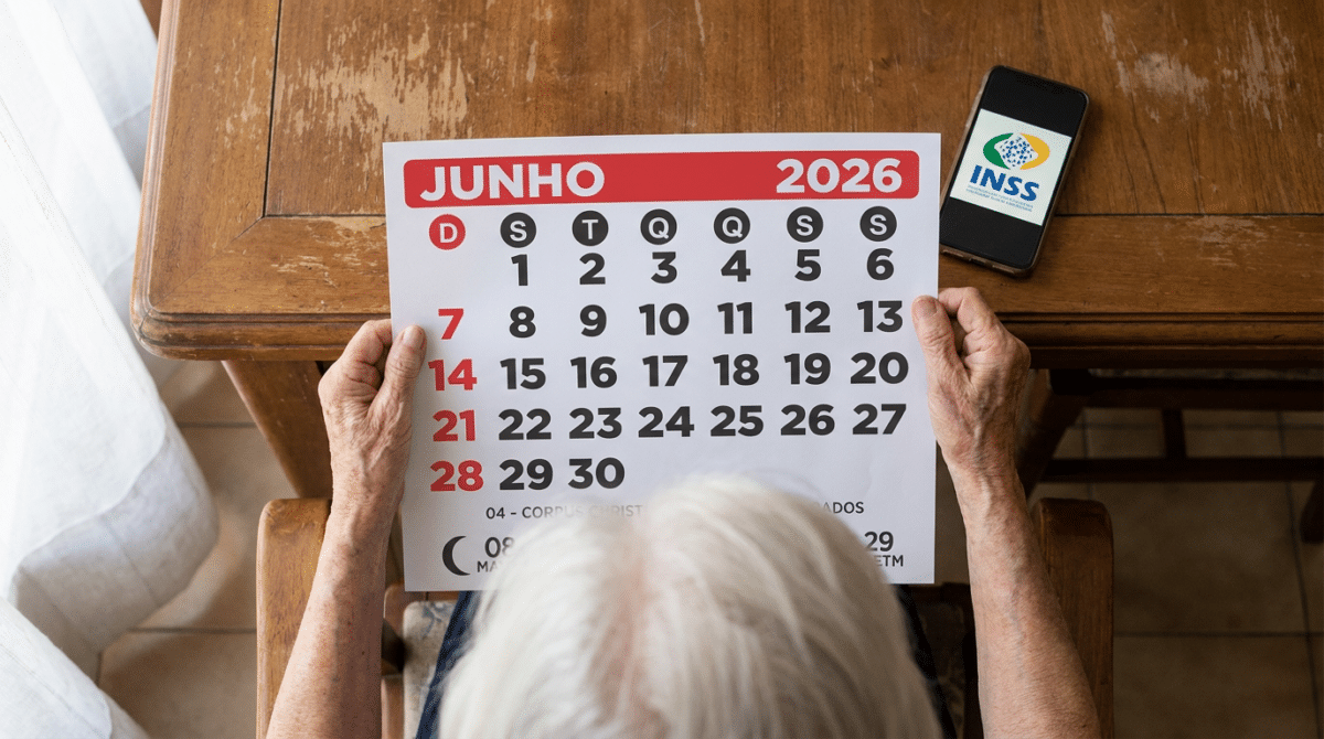Pessoa idosa com cabelos brancos segura calendário de junho 2026 sobre mesa de madeira, com celular exibindo logo do INSS.