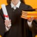 Recém-formada em Direito segura diploma e livros jurídicos representando as áreas de atuação além da advocacia