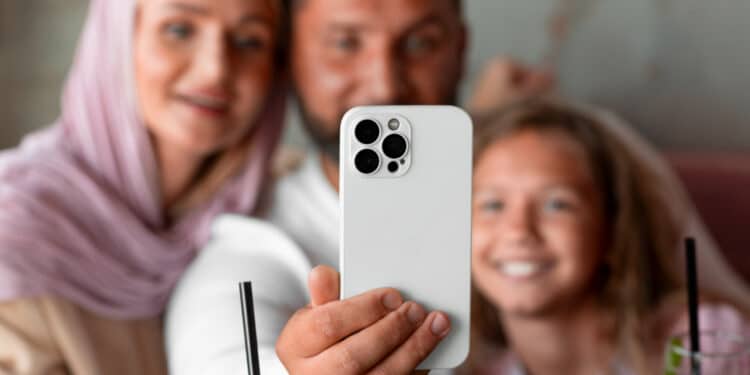 Família sorridente faz selfie com smartphone premium de câmera tripla em momento de lazer
