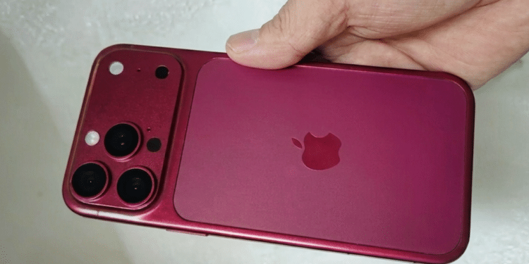 Mão segurando iPhone na cor vinho/burgundy com módulo de câmera tripla e logo da Apple visível.