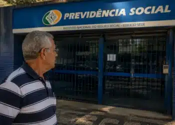 Idoso observando agência do INSS fechada, representando a suspensão de pagamentos de benefícios nesta quinta-feira, 4 de junho.
