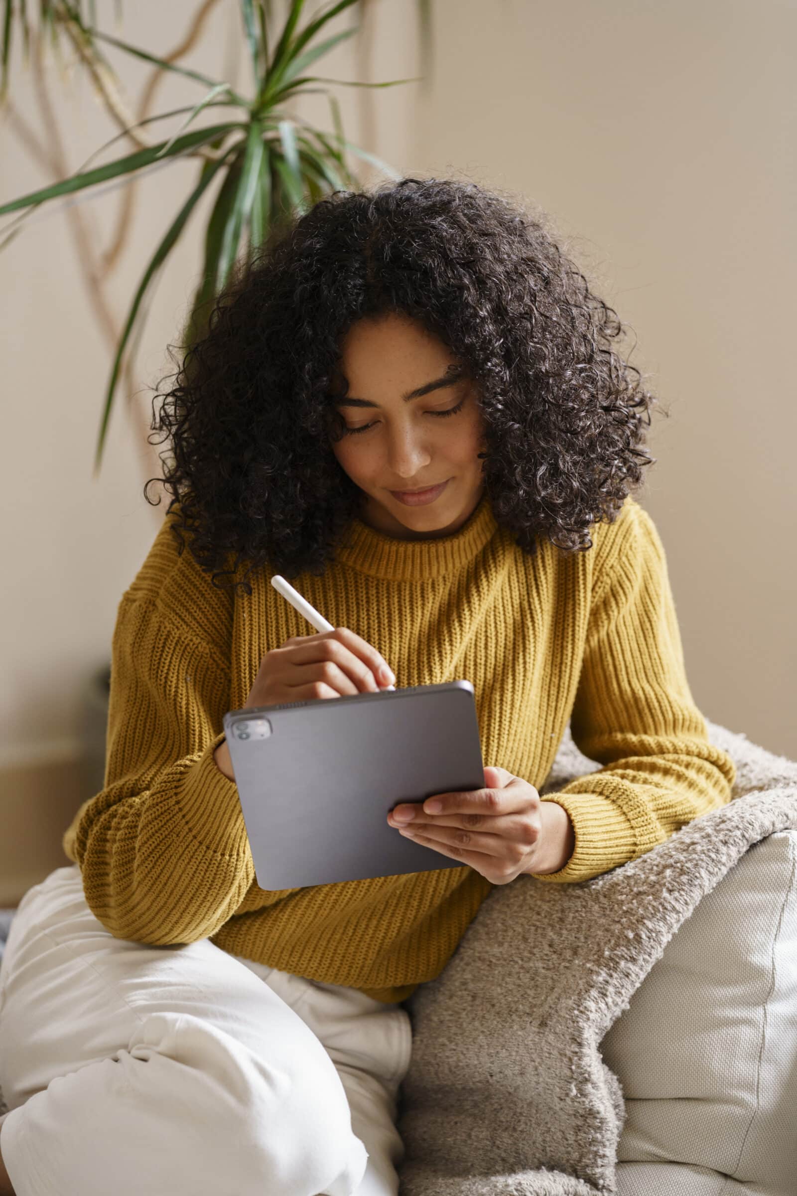 Mulher usa um iPad em uma mesa com notebook ao lado, avaliando se o iPad Air vale a pena