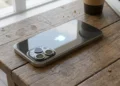 iPhone sobre mesa de madeira ilustrando modelos compatíveis com o iOS 27.