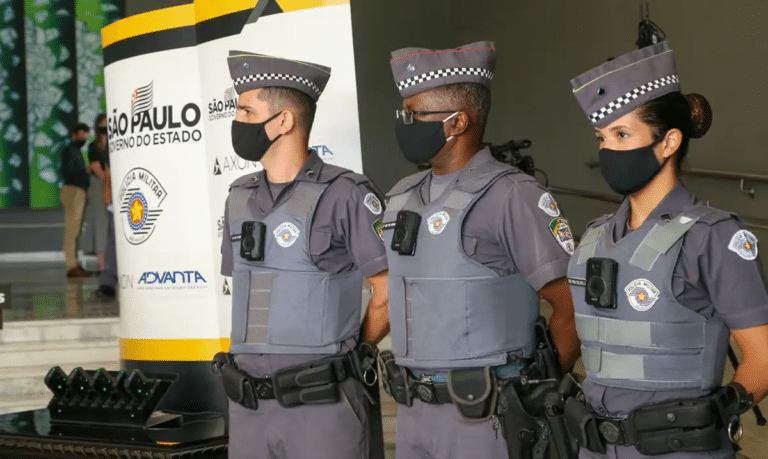 Três policiais militares de São Paulo, uniformizados e com coletes, em evento oficial do governo estadual